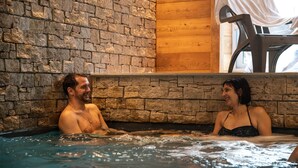 Een koppel in een jacuzzi met stenen muren en houten lambrisering.