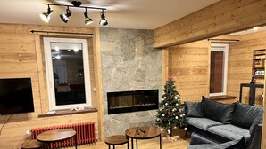 Een gezellige woonkamer met een stenen openhaard, een kerstboom en een moderne bank.