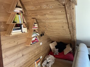 Une pièce mansardée chaleureuse avec des murs en bois, un plafond en pente et une bibliothèque intégrée.
