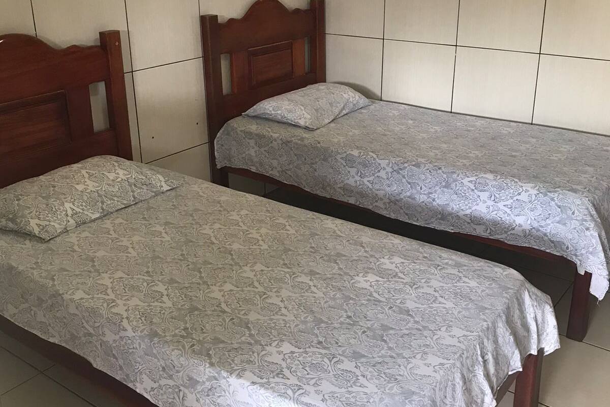 Two single beds with wooden headboards in a room with tiled walls and floor.