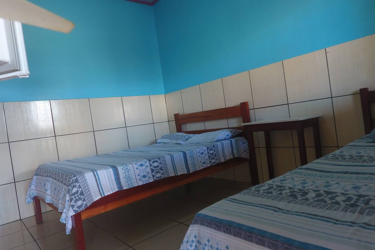 A room with two beds, a window, and tiled walls.