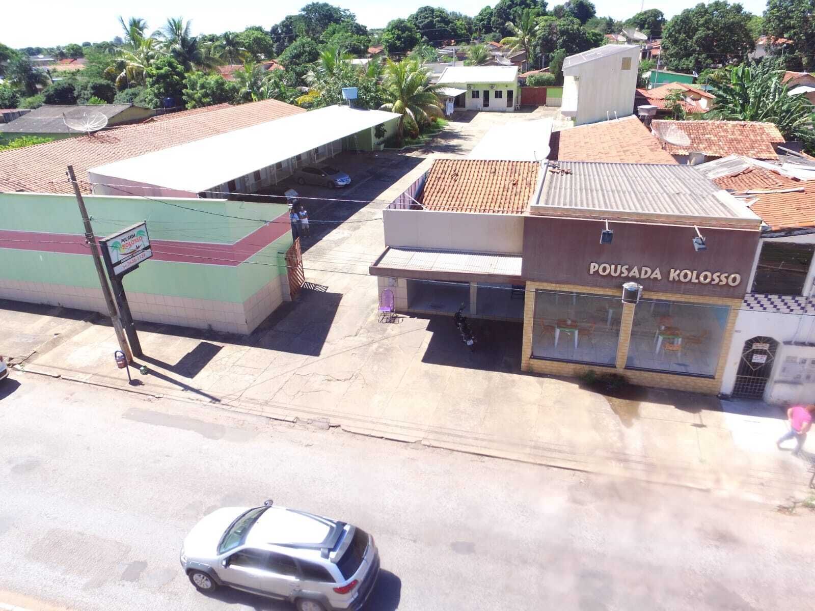Um edifício com uma placa que diz "Pousada Koloss" e um carro estacionado em frente.