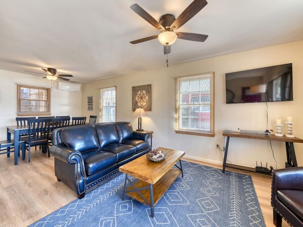 A living room with a dark leather sofa, wooden coffee table, and a ceiling fan.