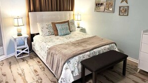 Ein Schlafzimmer mit einem Bett, Nachttischen, einer Bank und Wanddekorationen.