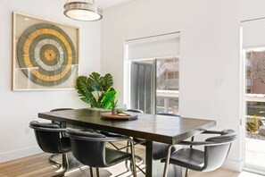Un espace repas moderne avec une table en bois foncé, des chaises noires et une plante en pot.