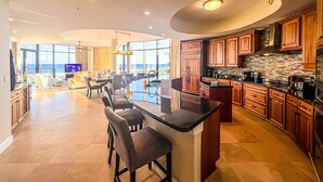 A modern kitchen with a large island, wooden cabinets, and a view of the ocean. - Where the Beach meets luxury! BEACHFRONT! (Pensacola)