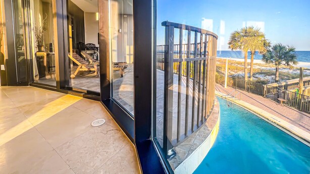 A modern pool area with a glass balustrade overlooking a beach. - Where the Beach meets luxury! BEACHFRONT! (Pensacola)