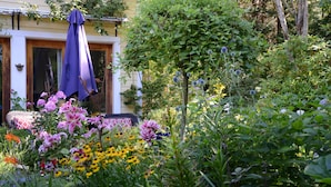 Jardí amb flors variades i una casa amb un para-sol morat.