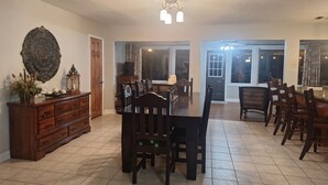 Un comedor con una gran mesa de madera y sillas, un aparador de madera y un espejo decorativo en la pared.
