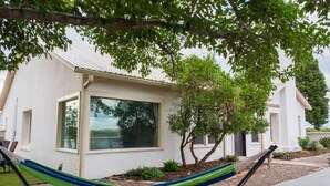 A modern house with a large window, a hammock, and a well-maintained garden.
