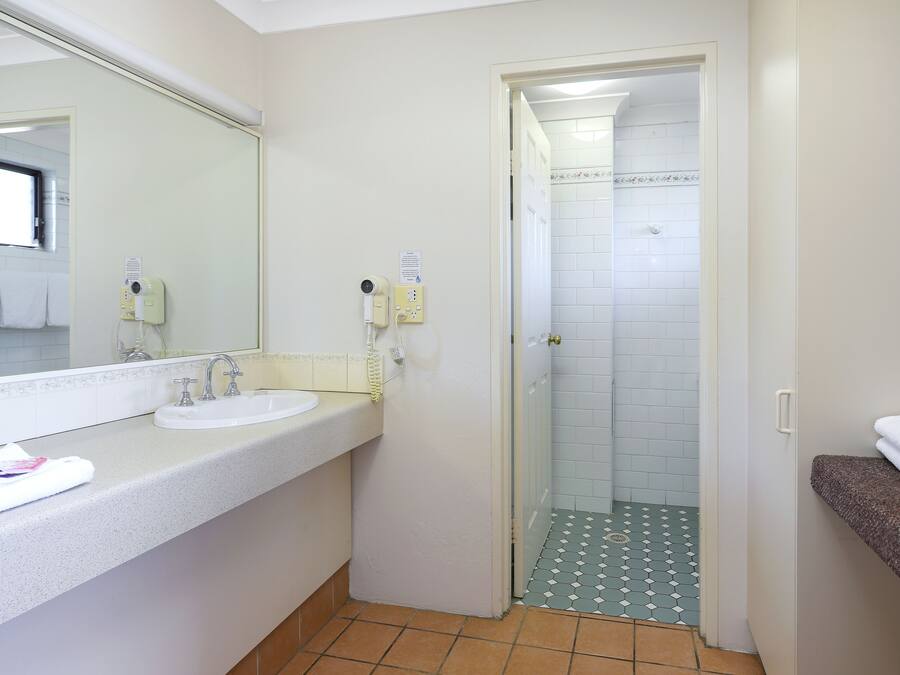 A bathroom with a white sink, a mirror, and a shower area.