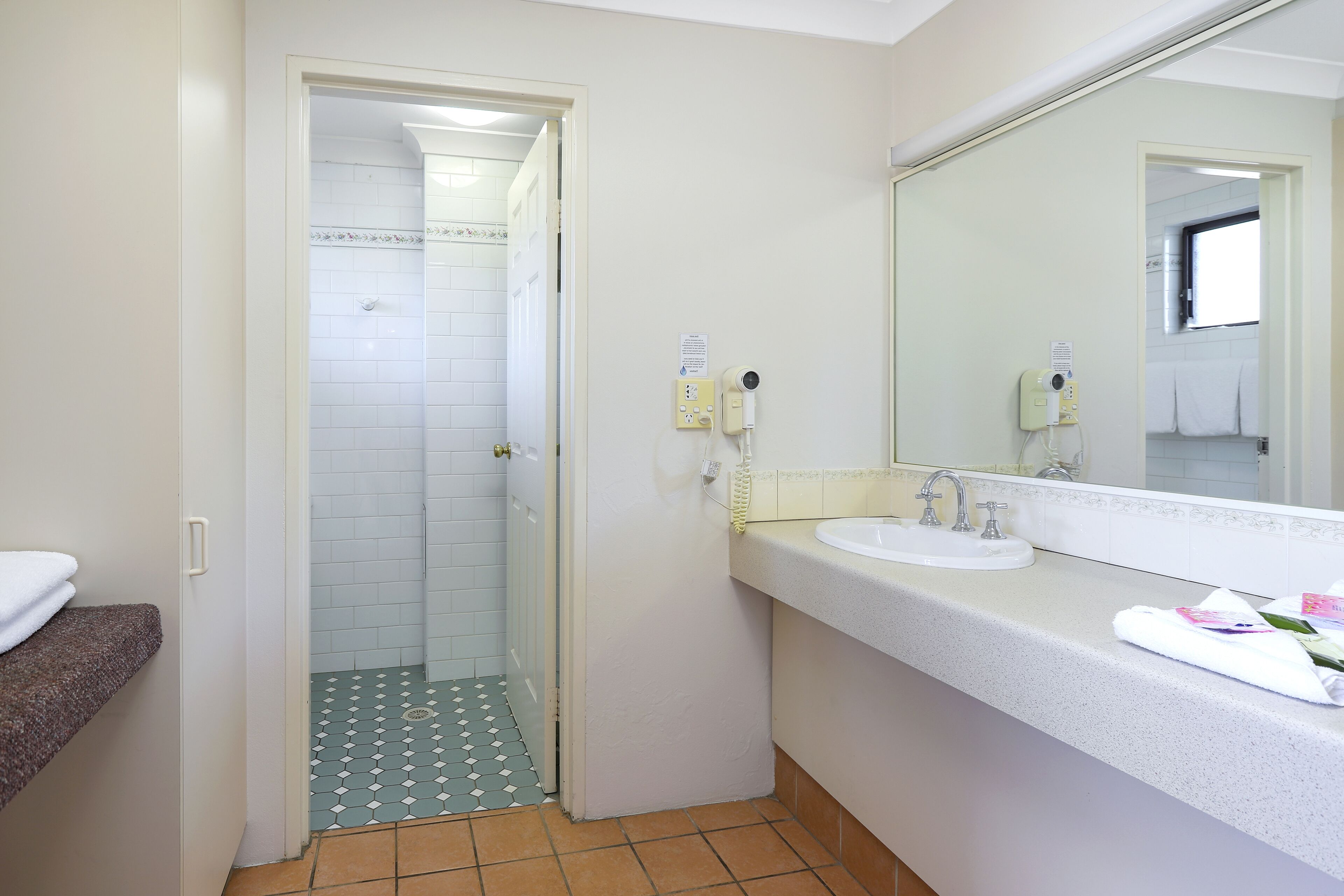 A bathroom with a white sink, a mirror, and a shower area.