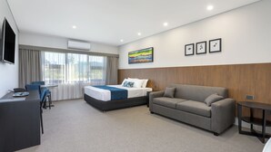 A modern hotel room with a bed, a sofa, a desk, and a TV. - Gateway Motel (Vineyard)
