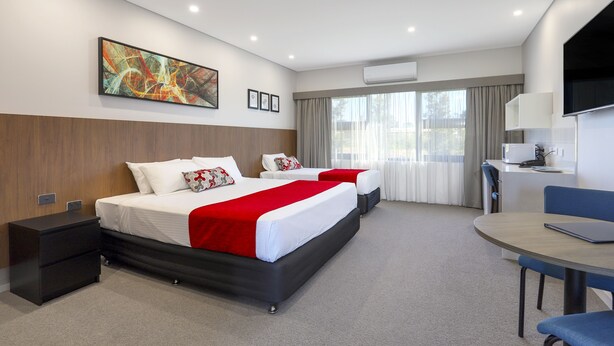 A modern hotel room with a large bed, a desk, and a TV. - Gateway Motel (Vineyard)