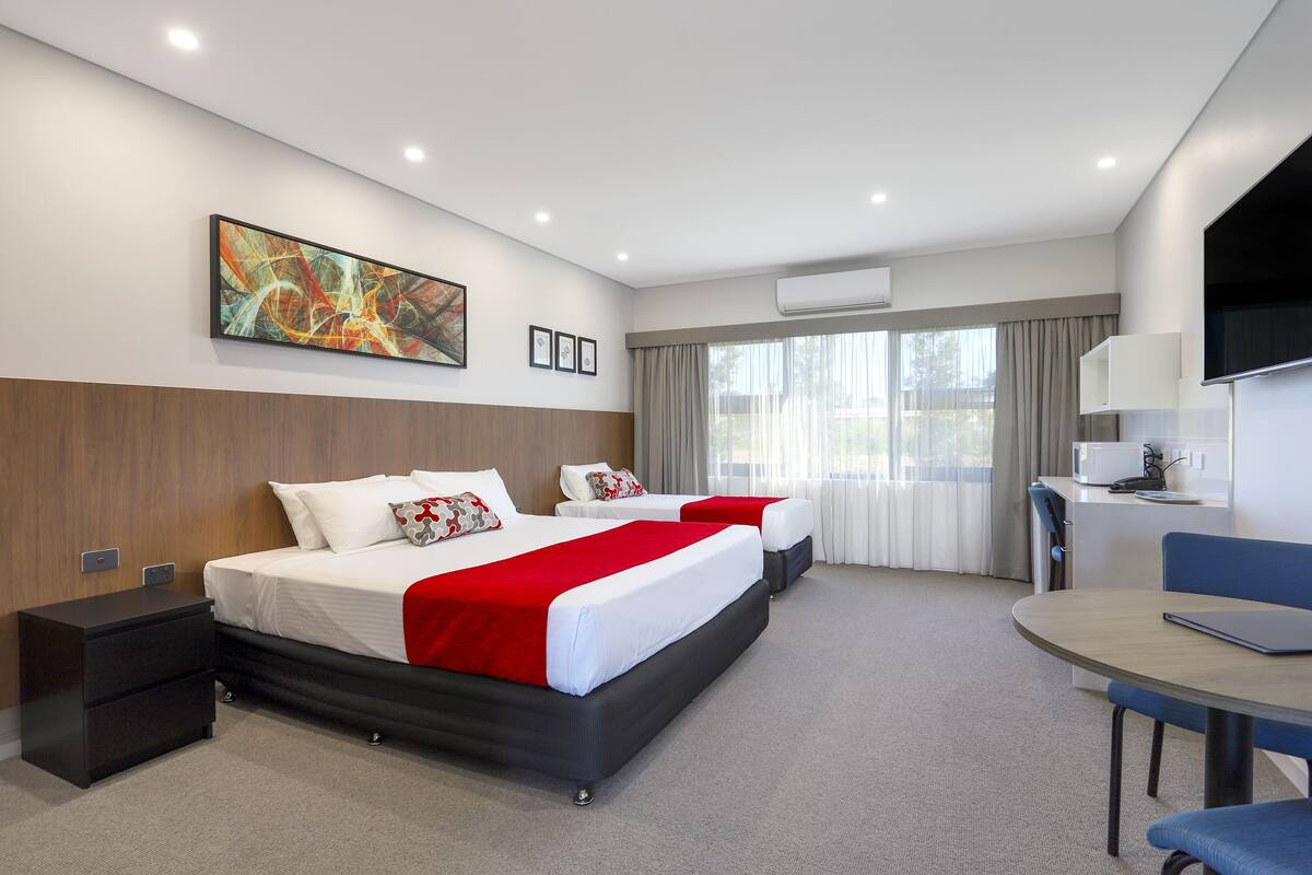 A modern hotel room with a large bed, a desk, and a TV.