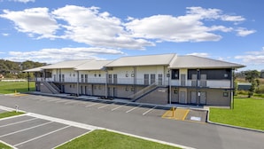 A multi-story motel with a parking lot in front. - Gateway Motel (Vineyard)