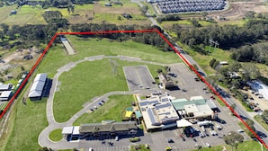An aerial view of a commercial area with a large parking lot, a building with solar panels, and a road network. - Gateway Motel (Vineyard)
