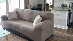 A modern living room with a sofa, a dining area, and a kitchen.