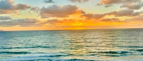 Una playa con olas y un atardecer.