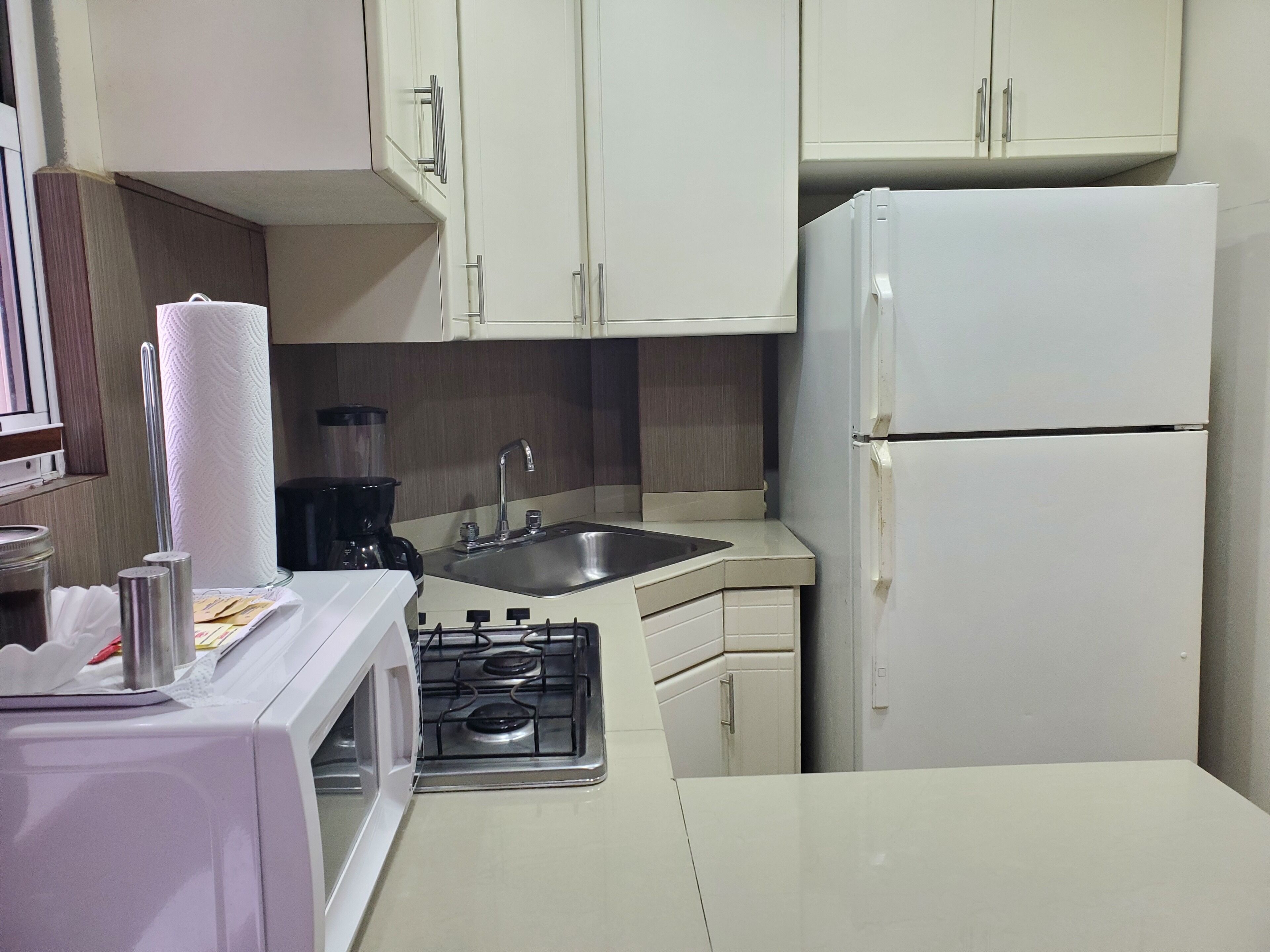A compact kitchen with white cabinets, a sink, a stove, and a refrigerator.