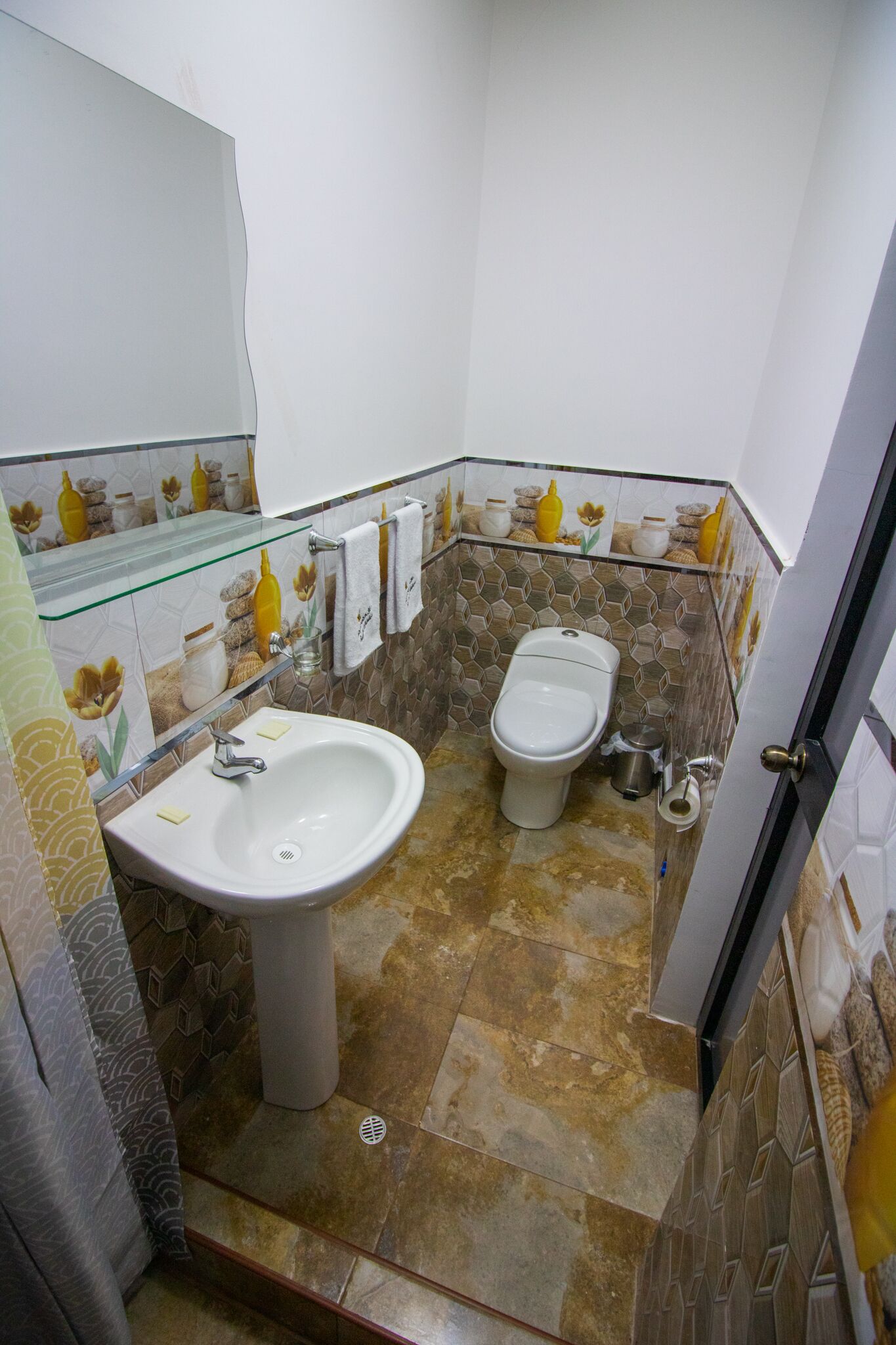 Een badkamer met een witte wastafel, een toilet en een bidet. De muren zijn betegeld met een patroon.