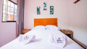 A hotel room with a wooden headboard, white bedding, two bedside tables, and artwork on the wall. - HOSPEDAJE SANTA MONICA (Tarapoto)