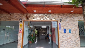 The entrance to a hotel named 'HOSPEDAJE Santa Monica' with a stone facade, glass doors, and a reception area visible inside. - HOSPEDAJE SANTA MONICA (Tarapoto)