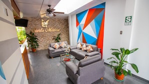 A modern lobby with grey sofas, a glass coffee table, and potted plants. - HOSPEDAJE SANTA MONICA (Tarapoto)