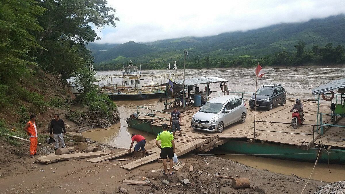 A riverbank with a dock, people, and vehicles.
