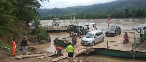 A riverbank with a dock, people, and vehicles.