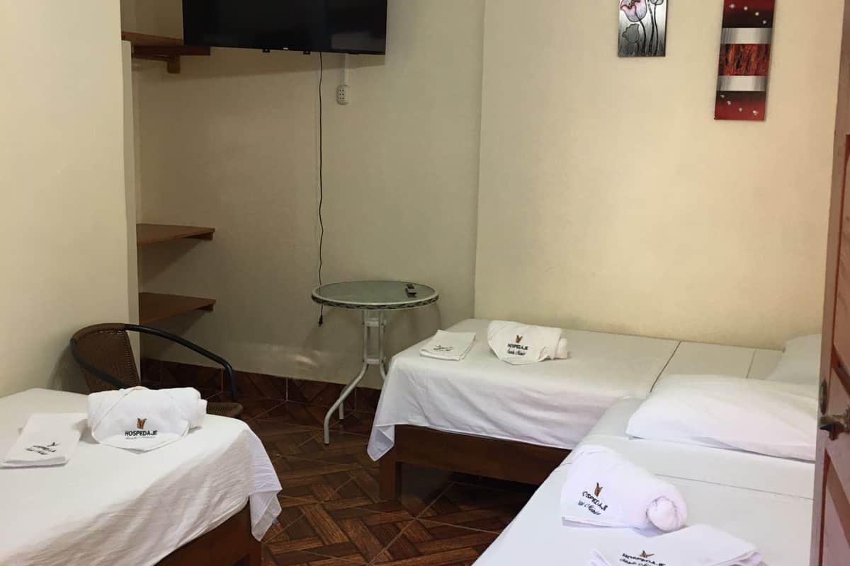 Une chambre d’hôtel avec deux lits, un ventilateur de plafond, un téléviseur fixé au mur et une petite table.