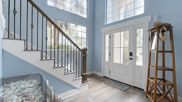 A staircase with a wooden handrail and black balusters, leading to a white door with glass panels. - Perdido Bay 4BR Waterfront House WITH A DOCK AND WHITE SANDS IN THE BACKYARD! (Pensacola)