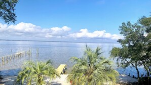 A beach with palm trees, a wooden structure, and a clear view of the water. - Perdido Bay 4BR Waterfront House WITH A DOCK AND WHITE SANDS IN THE BACKYARD! (Pensacola)