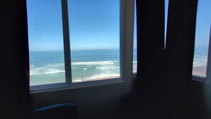 A room with a large window overlooking a beach and ocean. - Cozy apartment with a view (Tijuana)