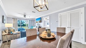 A dining area with a wooden table, six chairs, and a decorative centerpiece. - Gulf Views! Ground Unit! Patio! Ciboney 1002! (Miramar Beach)