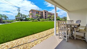 A balcony with a view of a green lawn and a multi-story building in the background. - Gulf Views! Ground Unit! Patio! Ciboney 1002! (Miramar Beach)