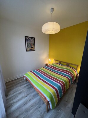 Un dormitorio pequeño con cama, un cartel en la pared y una lámpara colgante.
