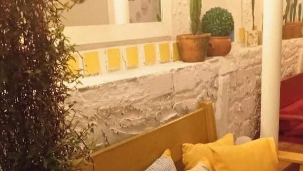 Una habitación acogedora con una cama de madera, almohadas amarillas y una pequeña planta en maceta.