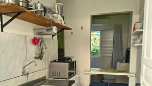 Una cocina compacta con estufa a gas, microondas y un pequeño comedor con dos taburetes.