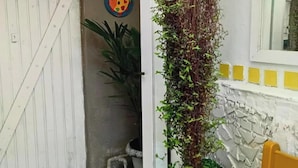 Una habitación con una puerta blanca, una planta colgante, un sofá amarillo y una pared de piedra.
