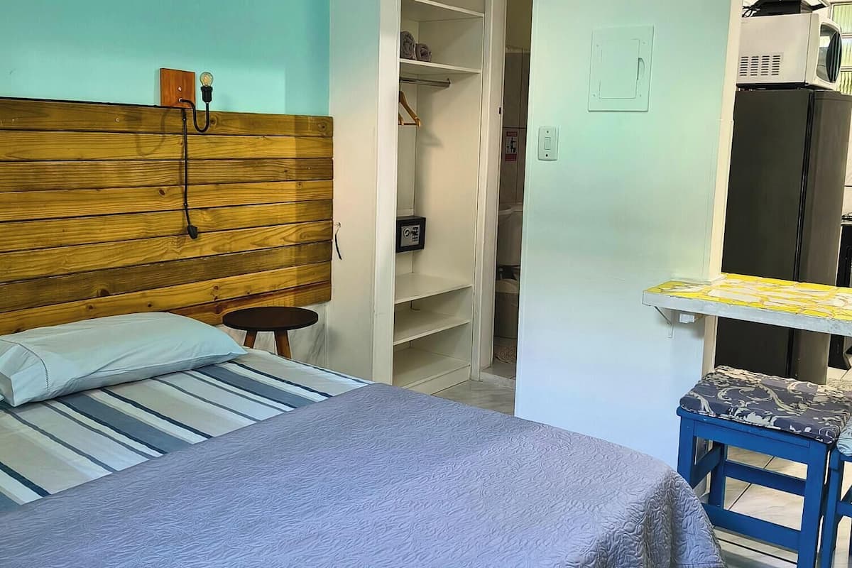 Ein Schlafzimmer mit einem Bett, einem Nachttisch, einem Kleiderschrank und einem kleinen Schreibtisch mit Stuhl.
