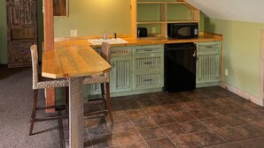 A compact kitchen with a wooden table and chairs, a built-in microwave, and green cabinetry. - Mountain View Apartment (Placerville)