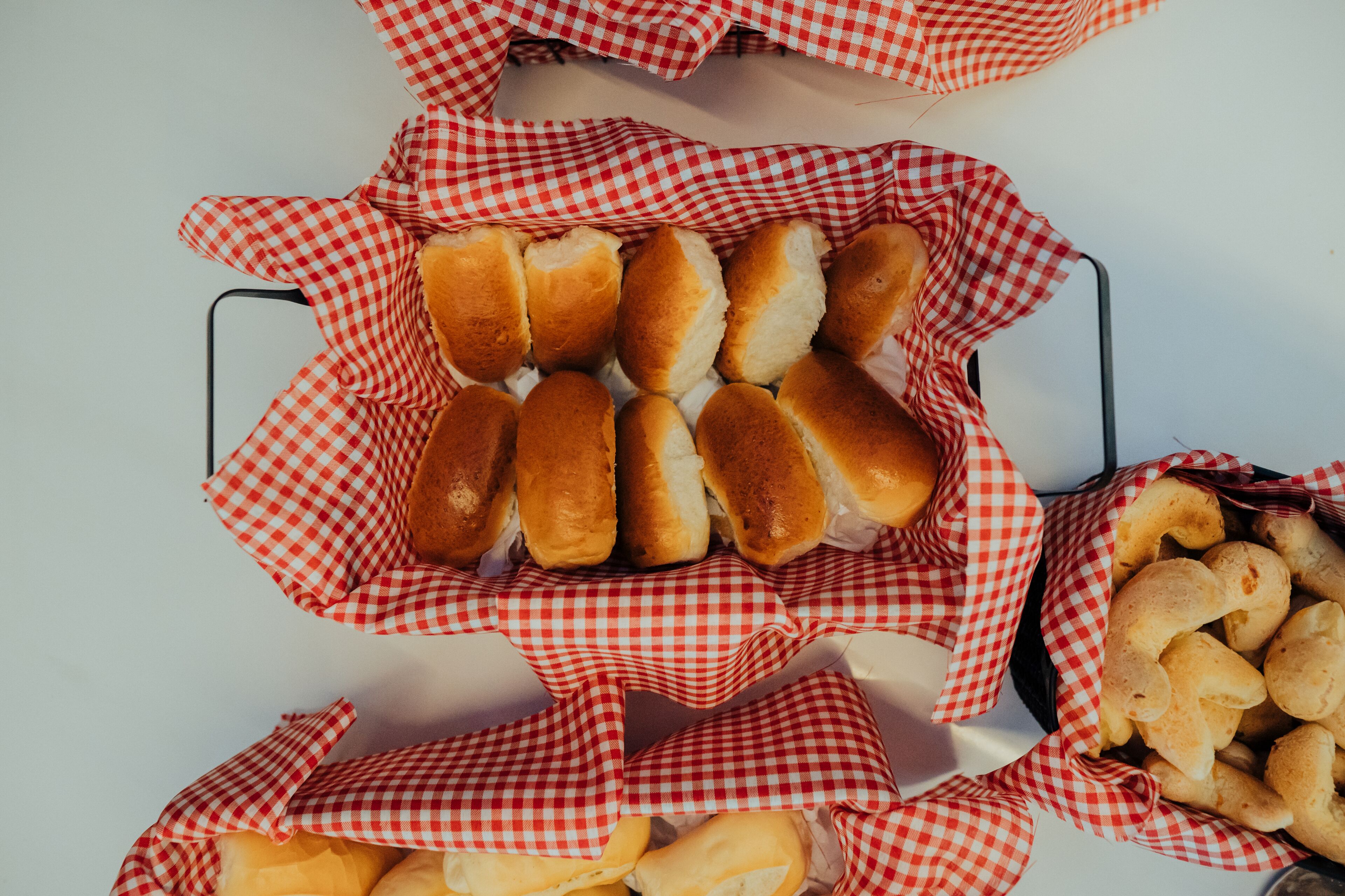 A tray of bread rolls and cheese sticks in a checkered paper basket.