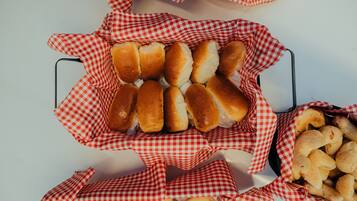 A tray of bread rolls and cheese sticks in a checkered paper basket.