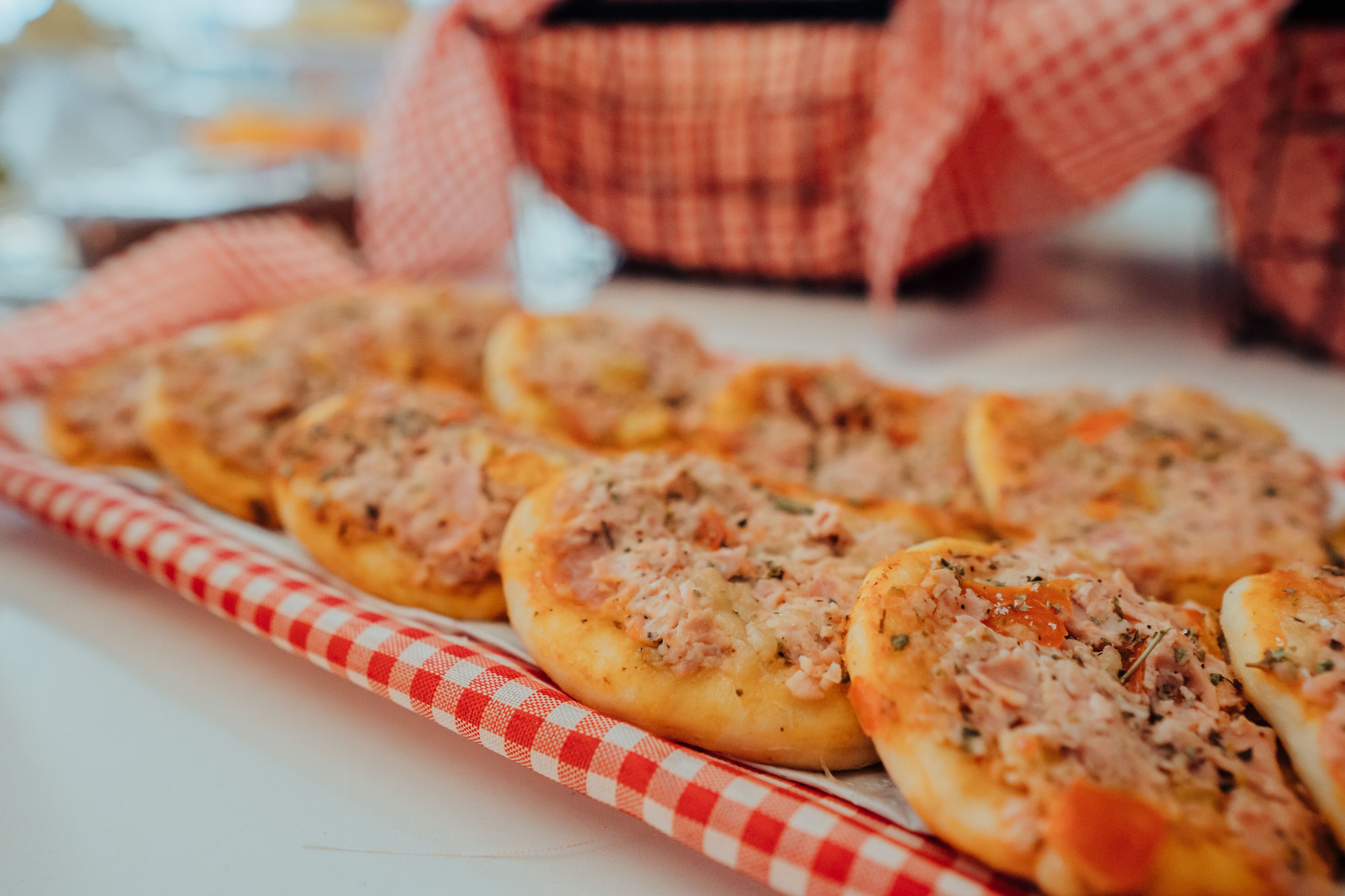 A tray of small pizzas with a checkered cloth underneath.