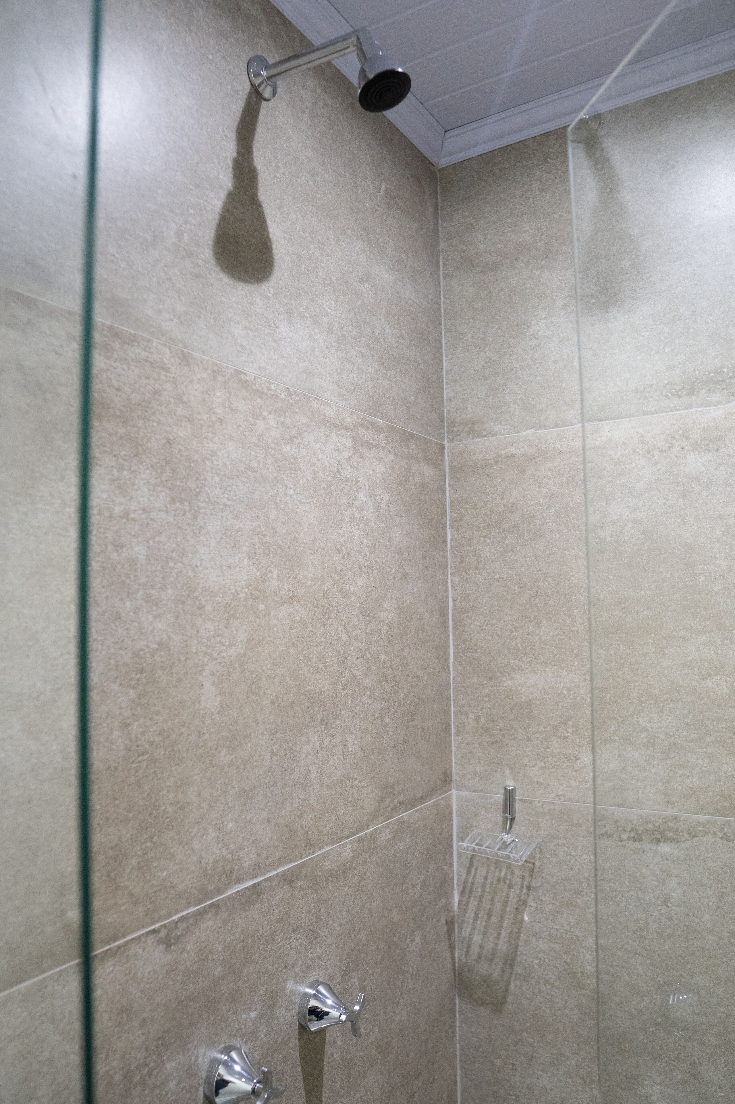Um banheiro moderno com box de vidro, porta-toalhas e chuveiro manual.