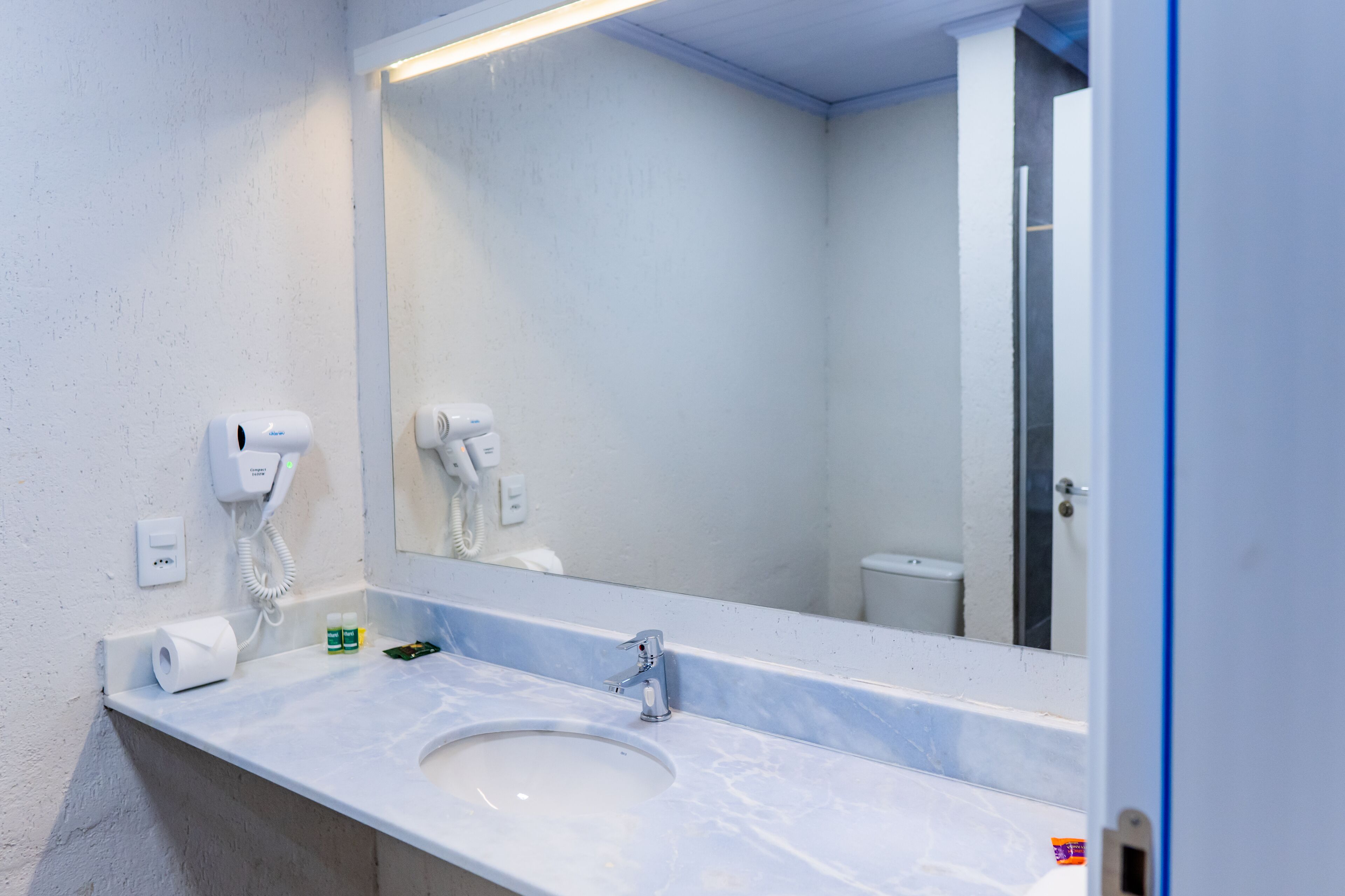 A bathroom with a sink, mirror, and hand dryer.