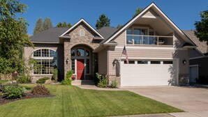 Une maison à deux étages avec une façade en pierre, une porte d’entrée rouge et un garage.