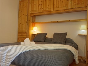 A wooden cabin-style room with a bed, two bedside lamps, and a wooden headboard.