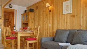 En inredning med träpanel, ett matbord, stolar, en soffa och en vägglampa.